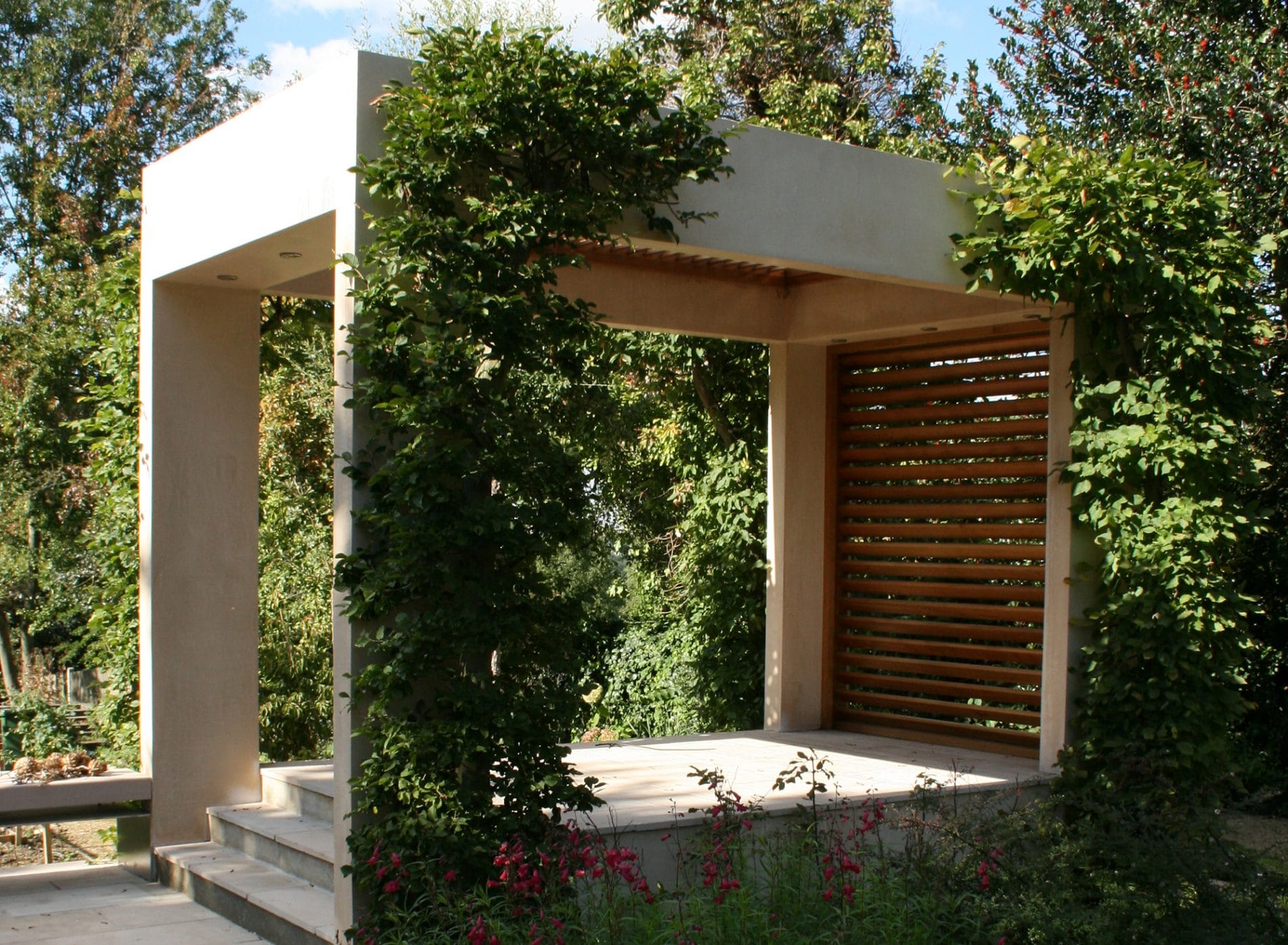 A view of the modern shelter with climbing plants in the arts and crafts themed garden