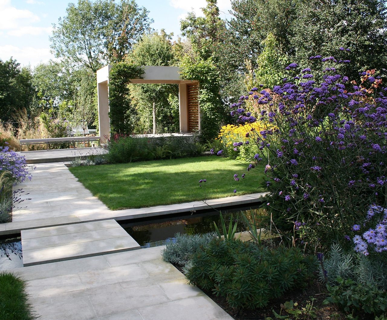 Formal arts and crafts style garden with paths and a canal running across it