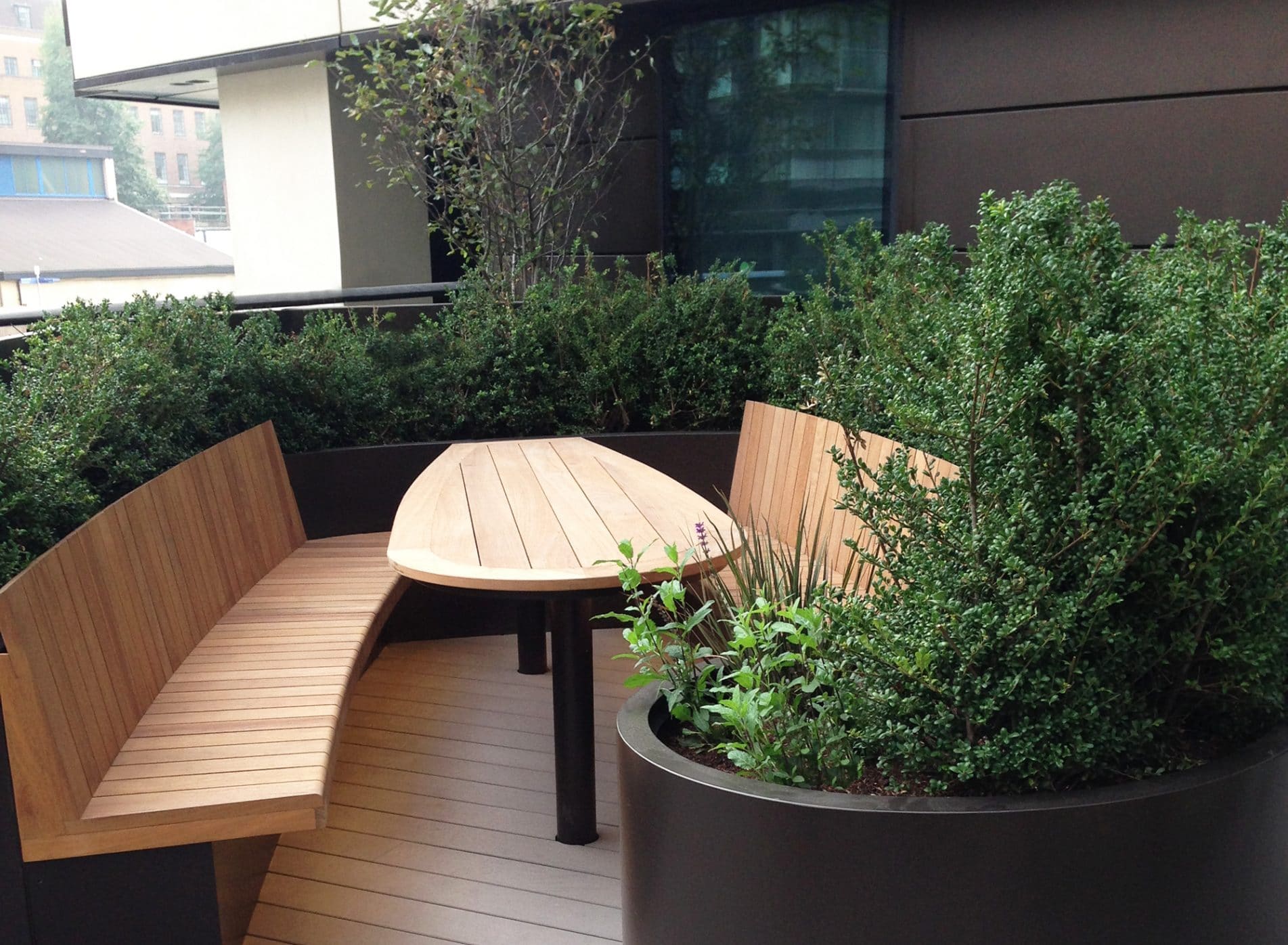 Bench and table area at Merchants Square with evergreen hedges surrounding it