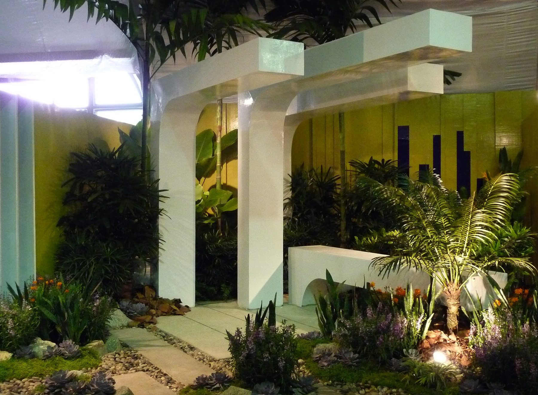 Tropical plants against the modern pergola with a bright yellow background