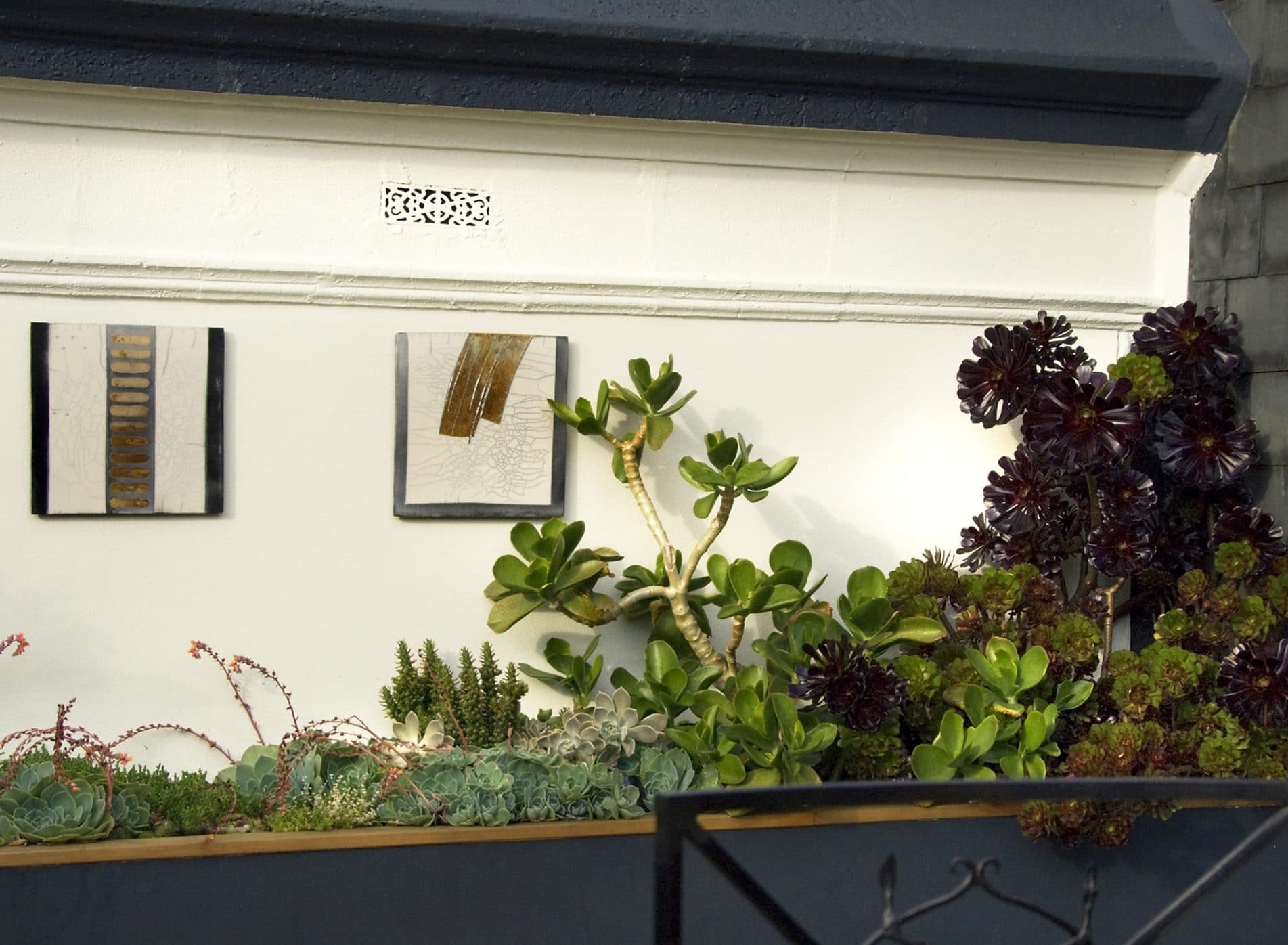 Detail of artistic tiles on the walls set against mediterranean style planting