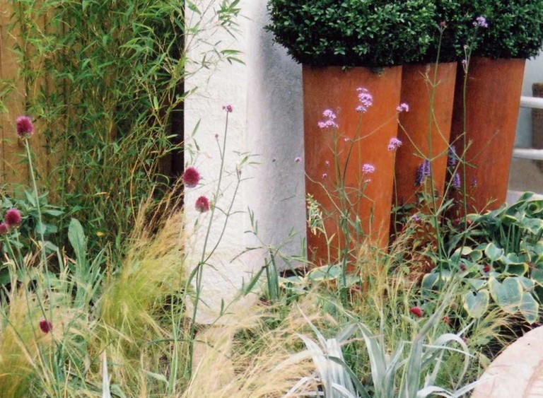 Terracotta planters surrounded by flowers and grasses