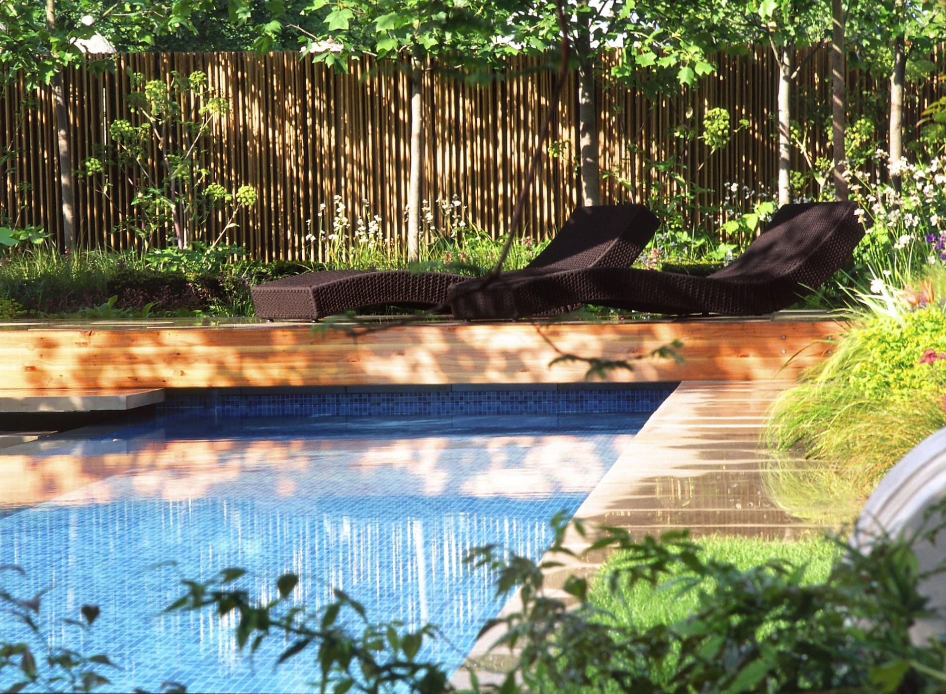 Sunloungers in dappled sunlight by the swimming pool - RHS Chelsea Flower Show 2006