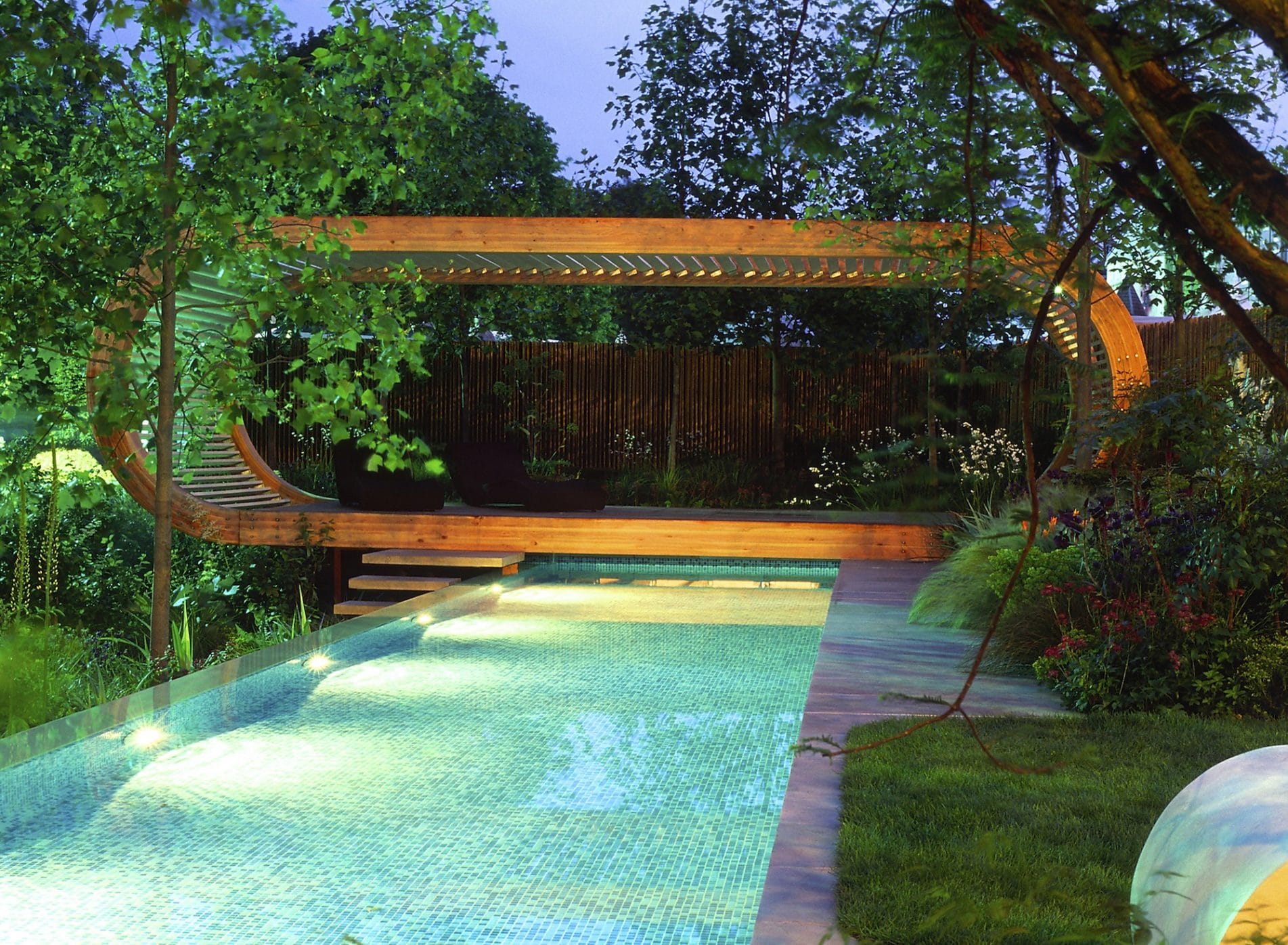 View of pavilion across swiming pool at dusk with lighting