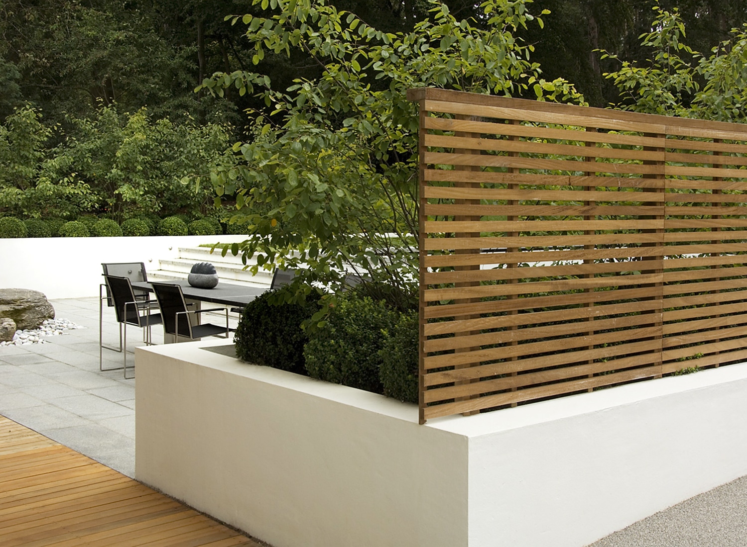 Dining patio area screened off by a fence and planting