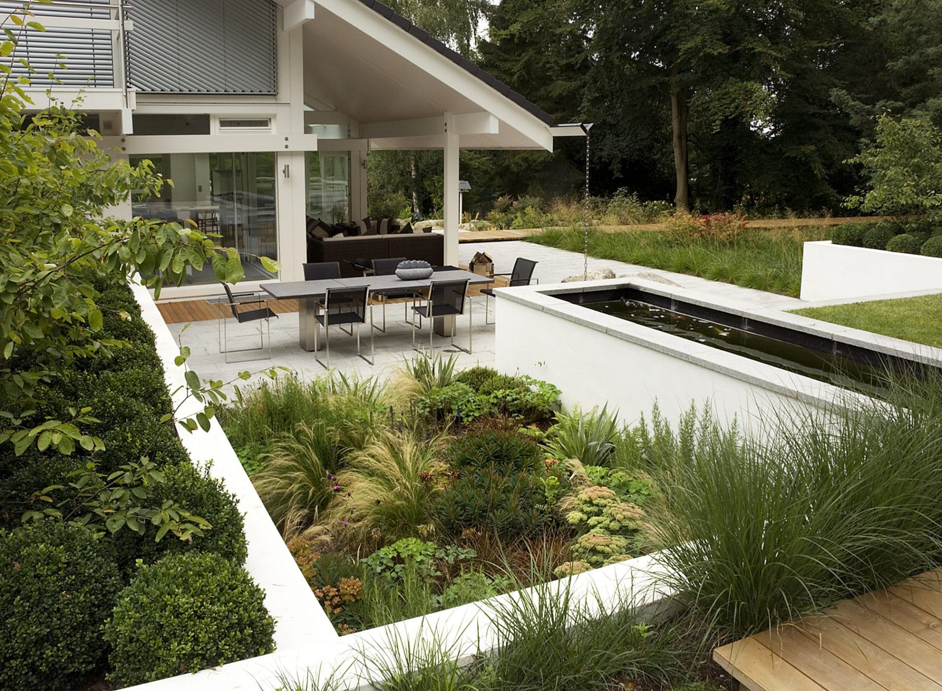 White walled planting areas filled with green shrubs and grasses