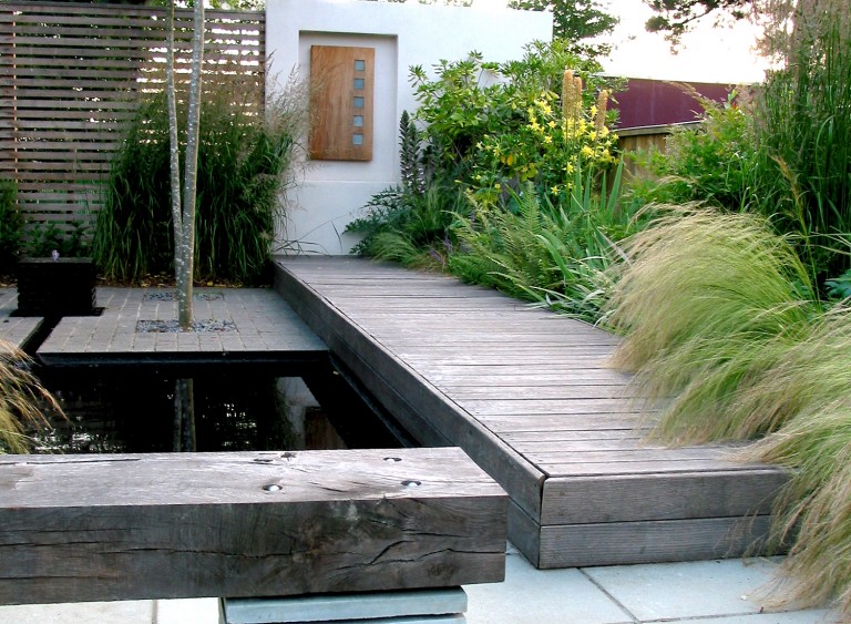 Bench made from a sleeper by a water feature and decking