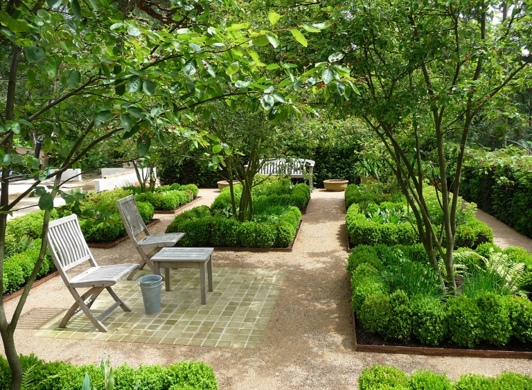 Wooden chairs in a parterre garden room with trees and herbs