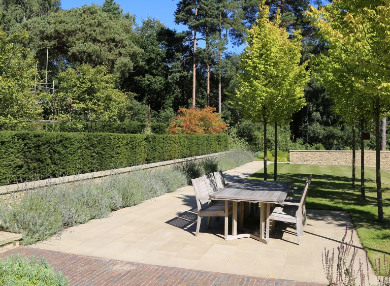 Outdoor dining table on a patio lined with lavender