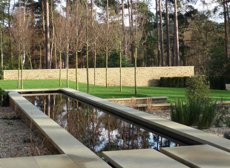 Water feature by a lawn, reflecting the trees