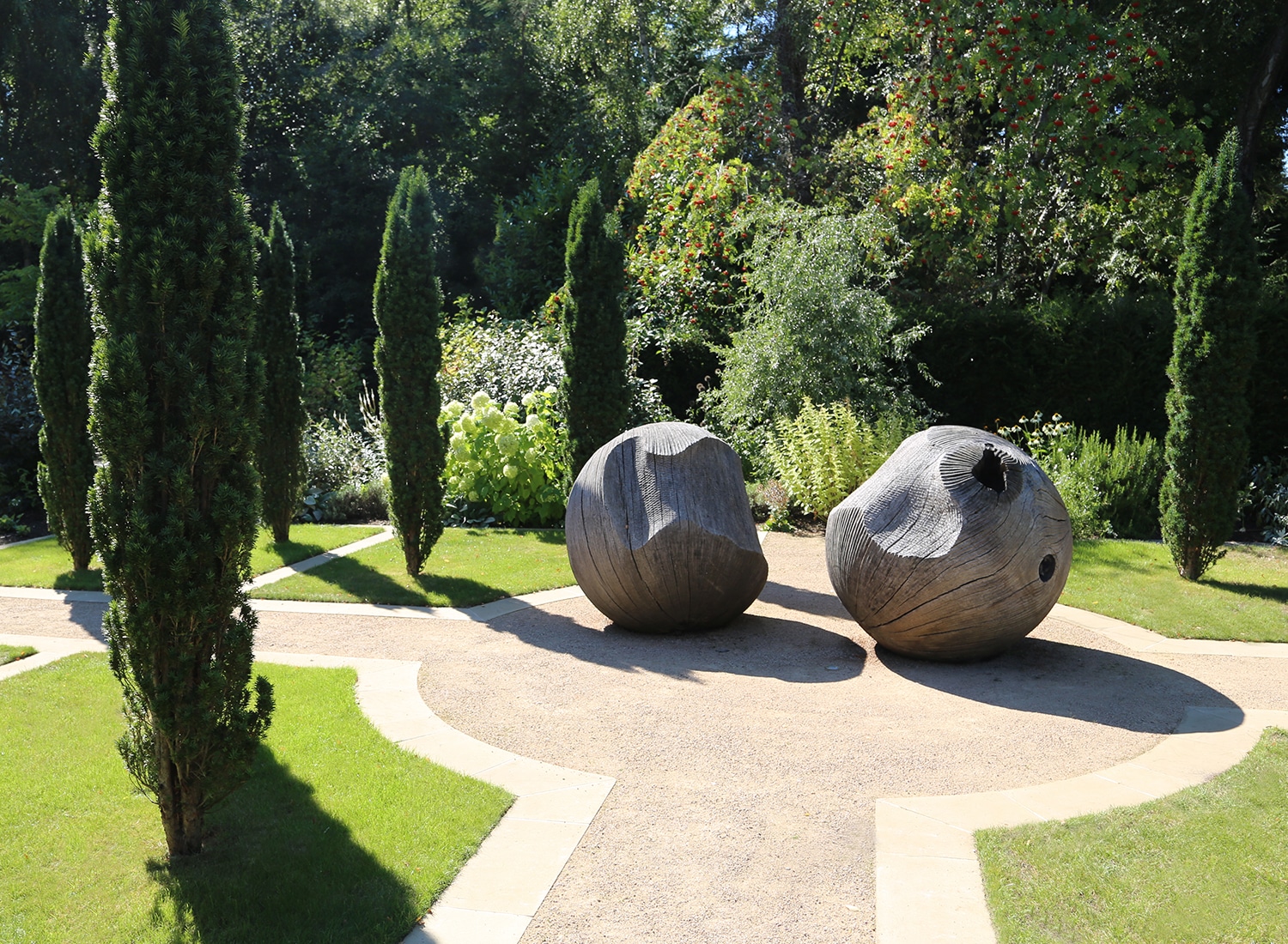 Two wooden sculptural ball shapes surrounded by trees