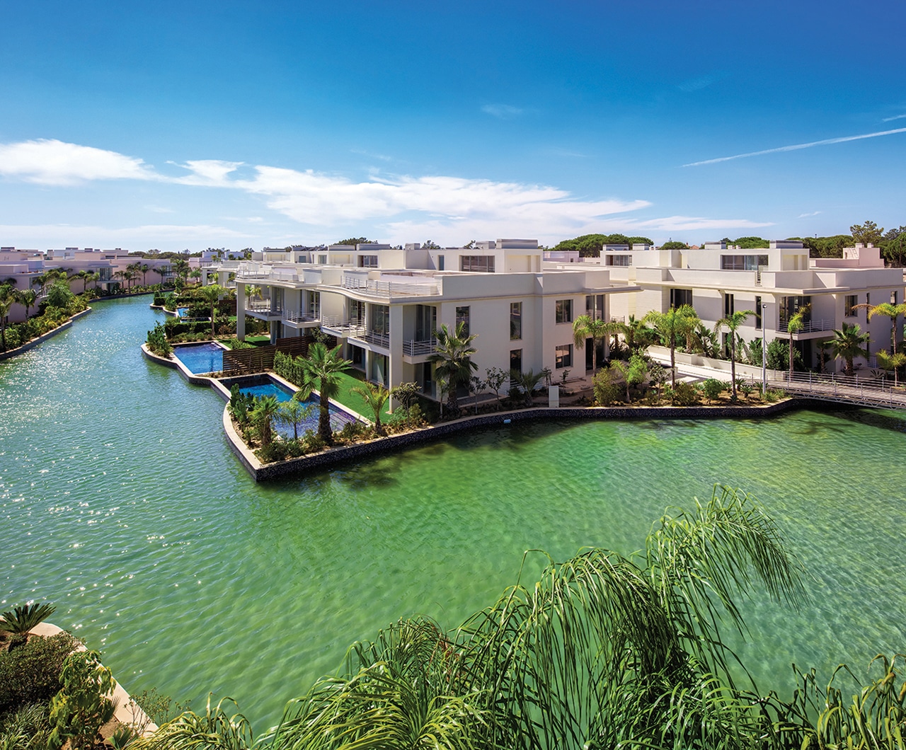 Modern Building Complex With Clear River Surrounding Featuring Palm Trees And Swimming Pools