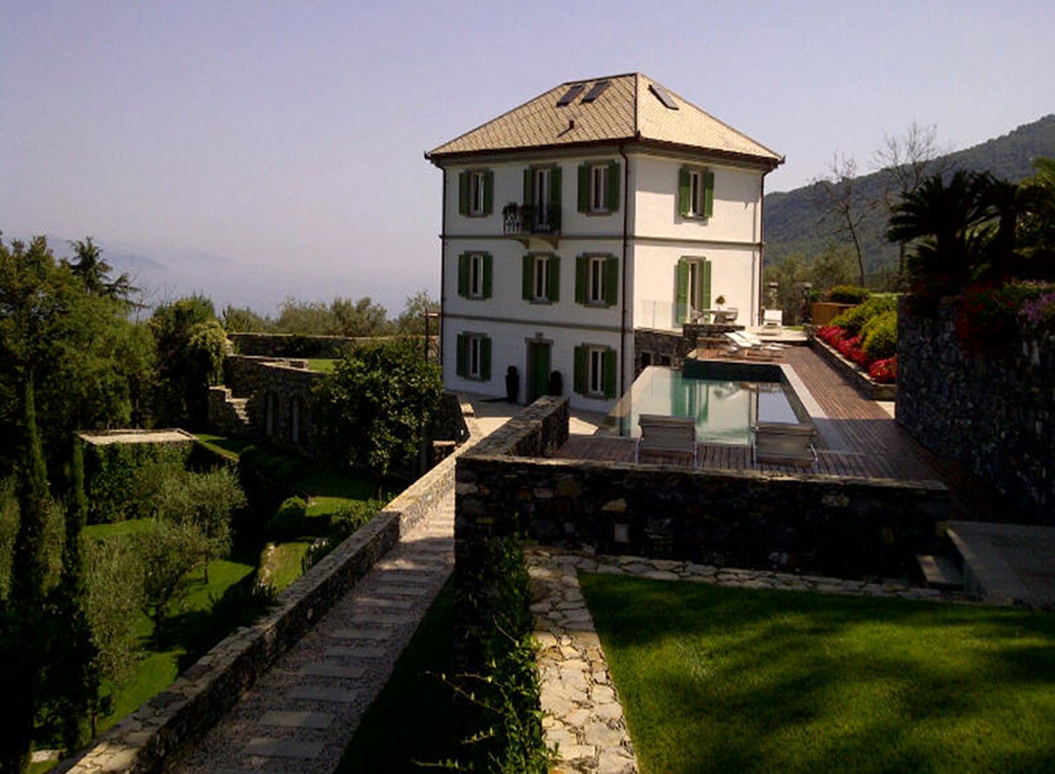 Mediterranean style planting with a path leading to the swimming pool and Italian villa