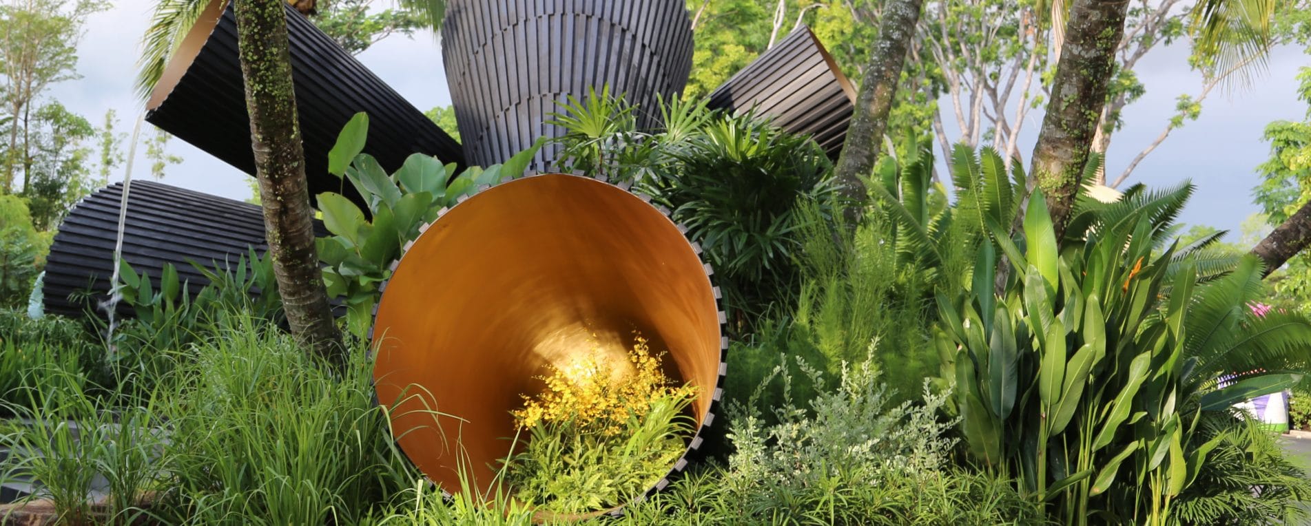 Modern Sculpture In Colours Of Black And Gold Featuring In A Bed Of Green Plants And Trees In Singapore