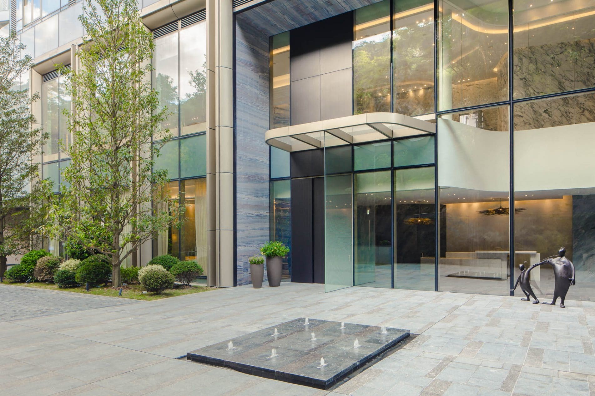 Luxury Residential Apartment Block In Hong Kong Featuring Front Fountain And Statues Of Two Figures