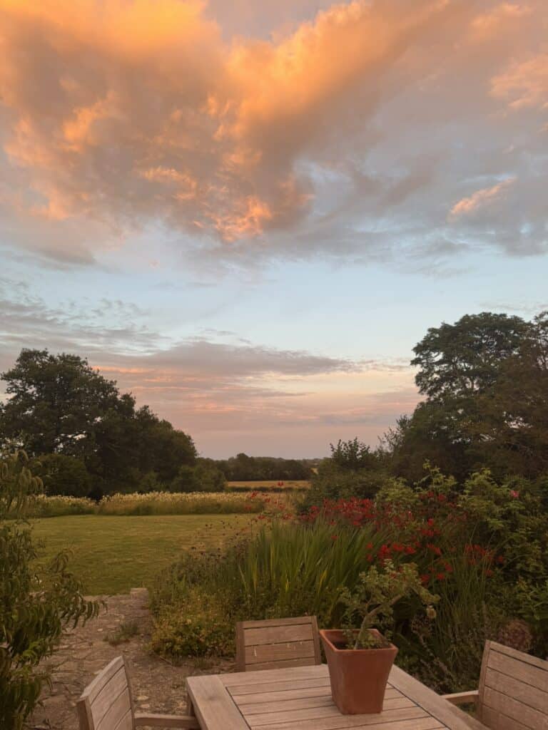 farmhouse with naturalistic garden and meadows at sunset